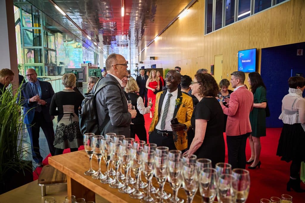 Group of people chatting, with champagne glasses in the foreground.