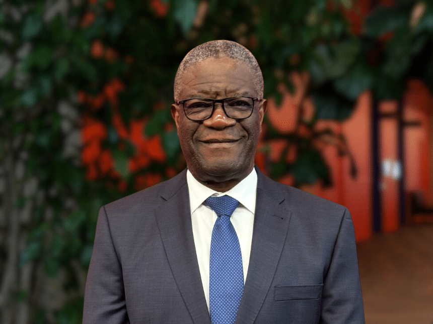 Portrait de Denis Mukwege avec un mur rouge et un arbre en arrière-plan.