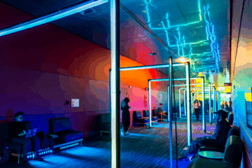 Couloir sombre avec une arcade de plusieurs néons de couleur bleu, vert, rouge et jaune
