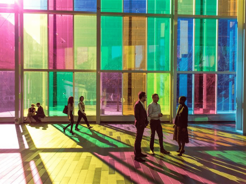 Several people walking in front of the colorful canopy