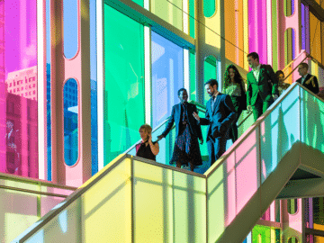 Groupe de personnes descendant les marches devant la verrière colorée.